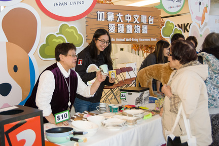 AM1470's Brenda Lo (left) and FM961's Cindy Wang (second from left) eagerly presented different styles of coffee mugs to a donor at Vancouver's charity sale booth on Oct 11. 